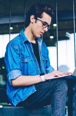 Konsantre erkek öğrenci web semineri izlemek için dizüstü bilgisayarda 4g kablosuz bağlı hipster adam internet web sitelerinde yararlı dosyaları arama ders çalışmaları nın bir bölüm için bilgi yazma