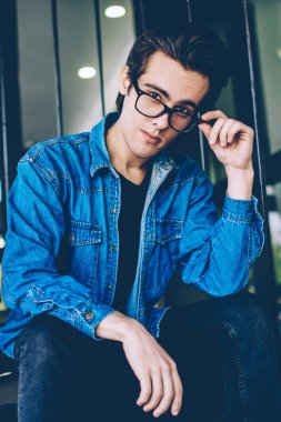 Boş zamanlarında açık havada kameraya bakarak gözleri koruma sağlamak için gözlük yakışıklı hipster adam Portresi, kampüs merdivenlerinde poz denim kıyafeti giymiş genç beyaz erkek genç