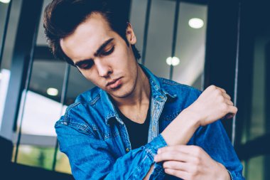 Boş zamanlarında modern kentsel ortamda otururken kot pantolon t shirt giyen şaşkın kafkas hipster adam, rahat denim giymiş genç düşünceli genç adam açık havada serbest zaman harcama bakmak