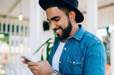 Siyah şapkalı bir Türk 'ün sosyal ağlardan en sevdiği blogcuya cep telefonuyla 4G kablosuz bağlantı kurduğu için kısa mesaj yazışının yan görüntüsü, mutlu adam arama telefonu numarası