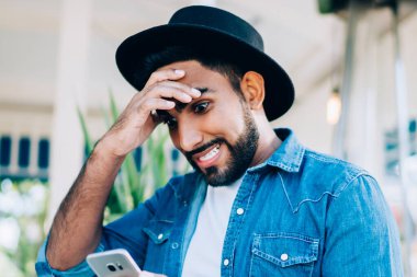 Kot giyim kuşamı giymiş hayret verici hipster blogcusu akıllı telefon zımbırtısında düşük şarjlı pil olduğu mesajıyla şok oldu. Şık kot gömlekli şaşırmış adam.