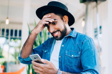 Kot giyim kuşamı giymiş hayret verici hipster blogcusu akıllı telefon zımbırtısında düşük şarjlı pil olduğu mesajıyla şok oldu. Şık kot gömlekli şaşırmış adam.