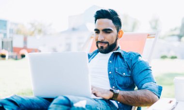 Üniversitenin kampüs bölgesinde dinlenen kaygısız hippi üniversite arkadaşlarıyla online sohbetten keyif alan, yeni web mağazaları arayan mutlu bir Türk.