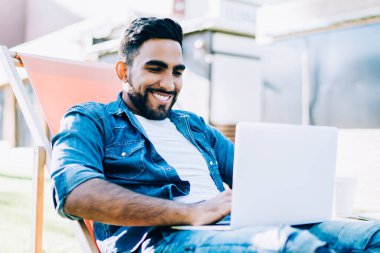 Mutlu adam, arkadaşının mesajını okurken gülümsüyor. İnternet sitesinden laptoptaki internet bağlantısı için metin içeriğini arıyor. Çevrimiçi iletişim kavramı.