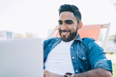 Neşeli sakallı bir adam kendi blog sayfasında yayınlamak için metin bilgileri yazıyor olumlu eleştiriler ve yorumlardan kendini iyi hissediyor, mutlu erkek serbest çalışan dizüstü bilgisayardaki internet sitelerini tarıyor.