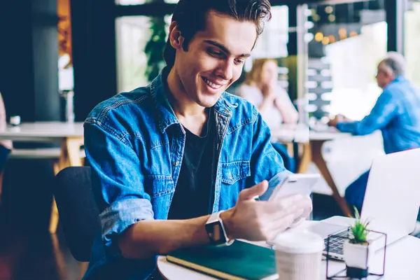 Kafeterya ücretsiz kablosuz bağlantı kullanarak mobil uygulama üzerinden komedi gösterisi online izlerken Neşeli hipster adam, sosyal ağ için app yeni bildirim iyi duygu gülümseyen erkek blogger