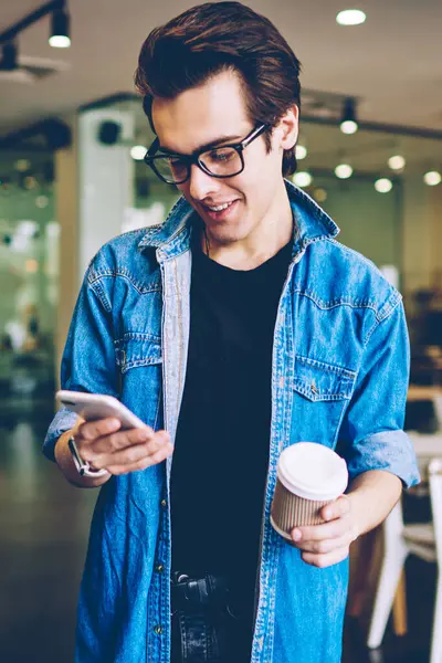 Kafeteryada kahve molası sırasında, teknoloji ve iletişim kavramını kullanarak sosyal ağda içerik metni içeren mutlu bir erkek blog yazarı yayınlıyor.