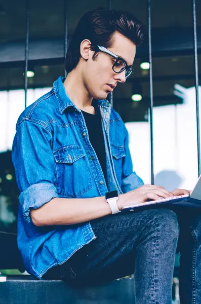 Konsantre erkek öğrenci web semineri izlemek için dizüstü bilgisayarda 4g kablosuz bağlı hipster adam internet web sitelerinde yararlı dosyaları arama ders çalışmaları nın bir bölüm için bilgi yazma