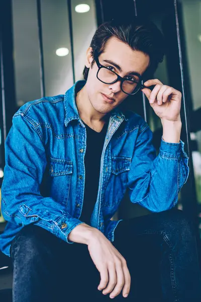 Boş zamanlarında açık havada kameraya bakarak gözleri koruma sağlamak için gözlük yakışıklı hipster adam Portresi, kampüs merdivenlerinde poz denim kıyafeti giymiş genç beyaz erkek genç