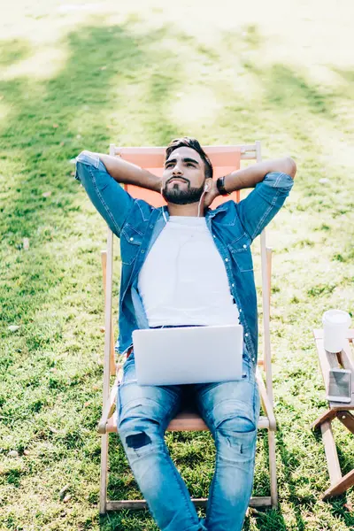 Sıradan bir kot giyip hayatın ve yaz havasının tadını çıkaran yakışıklı Türk 'ün en iyi görüntüsü. Milenyum hipster' ı dışarıda dinleniyor. Laptop kullanarak pozitif sesli kitap dinliyor.