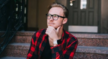 Yakışıklı, şık kıyafetli, gözlüklü, çenesini ovuşturan ve sıcak içecekten hoşlanan ve not defterine not alan yakışıklı bir adam.