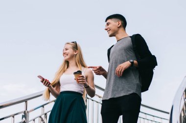 Gündüz vakti merdivenlerden cep telefonu ve dondurmayla inen sıradan giyinen genç adam ve kadının alçak açısı.