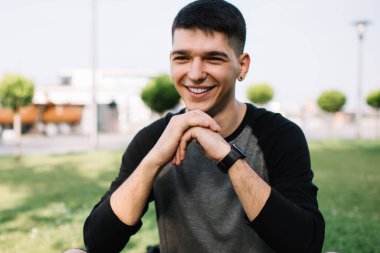 Parktaki çimenlerde dinlenirken çenesi ellerinin üzerinde kız arkadaşını neşeyle dinleyen kaygısız gülen adam.