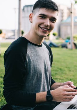 Milenyum çağındaki gündelik hipster bir adamın portresi dijital cep telefonunu elinde tutuyor ve boş zamanlarında dizüstü bilgisayarın güncellenmesini bekliyor. Modern teknolojileri kullanan pozitif erkek serbest yazar.