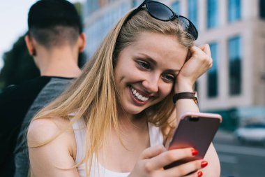 Cep telefonu cihazıyla samimi hippi kız internet sitesinde komik içerik yayınları okuyor. Modern akıllı telefon ve 4G kablosuz internet kullanıyor. Cep telefonlu mutlu kadın alışverişi yapıyor.