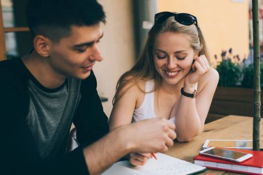 Kadın ve erkeğin kafeteryada özel ders için vakit geçirmesi ve üniversite sınavlarına bilgi kitaplarıyla hazırlanması, mutlu öğrencilerin ev ödevi yapma sürecinden hoşlanması.