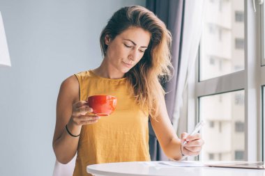 Aile etkinliği için günlük kıyafet planlama organizasyonunda endişeli bir kadın dizüstü bilgisayarla evde otururken, ciddi bir beyaz kadın mali bütçeye odaklanmış durumda.