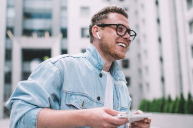 İş bölgesinde video oyunu oynamak için tablet kullanan günlük giysiler ve kulaklık takan içerikli adamın görüntüsü