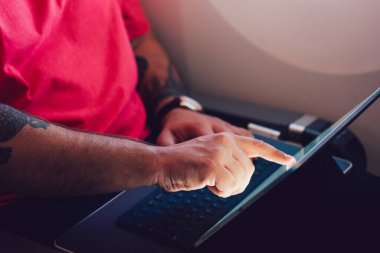 Beyaz erkek uçak yolcusu, kabinde uçak penceresinin yanında otururken ekranda parmak ile tablete dokunuyor, erkek, kablosuz internet bağlantısı ile uçuşun keyfini çıkarıyor.
