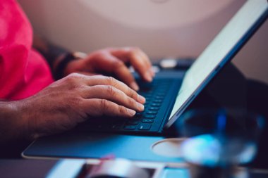 Uçaktaki kablosuz internete dokunmatik ped ile bağlanan genç bir uçuş yolcusu uçak kabin penceresinin yanında oturuyor. Ağ şablonu için boş ekranı, serbest çalışma için dijital göçebe işini düzenle