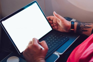 Uçaktaki kablosuz internete dokunmatik ped ile bağlanan genç bir uçuş yolcusu uçak kabin penceresinin yanında oturuyor. Ağ şablonu için boş ekranı düzenle, kalem ile tablete dokun
