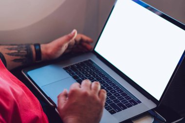 Uçaktaki kabin penceresinin yanında otururken laptopla kablosuz internete bağlanan genç adam uçuş yolcusu. Ağ şablonu için boş ekranı, serbest çalışma için dijital göçebe işini düzenle