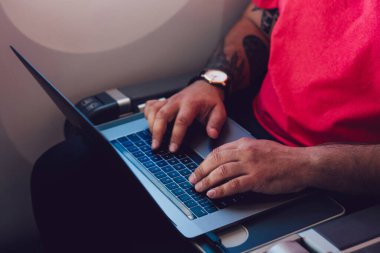 Uçaktaki kabin penceresinin yanında otururken dizüstü bilgisayarla kablosuz internete bağlanan genç adam uçuş yolcusu. Dizüstü bilgisayarda metin yazılıyor, dijital göçebe serbest çalışıyor