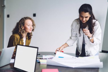 Gülümseyen çok ırklı genç erkek ve kadınlar sınıfta toplanıyor ve kağıt üzerinde proje yazımı üzerine yeni bir fikir yaratıyorlar.