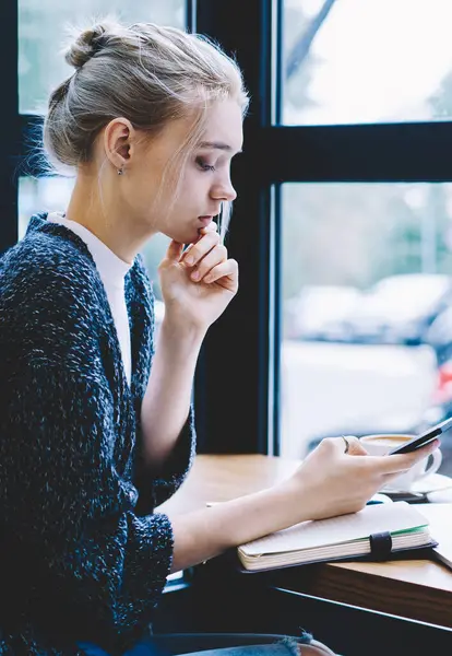 Cep telefonu ile ağ tarama yaparken akıllı telefonda video içeriği izlerken kadın. Kahve dükkanı iç otururken hücresel üzerinde internet sörf gülümseyen milenyal teknoloji Kullanıcı