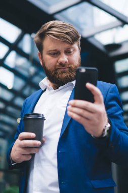 Kafkas erkek girişimci kahve ile gitmek ve modern akıllı telefon aygıtı ekranda bakıyor ve modern cep telefonu için güncelleme bildirimi ciddi mali uzman cep telefonu metin arama uygulaması