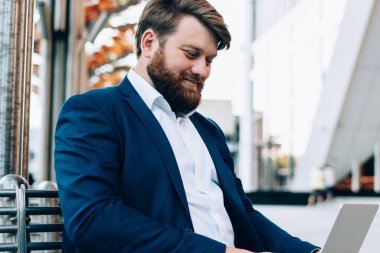 Resmi olarak giyimli iş adamı şehir ortamında oturuyor ve modern dizüstü bilgisayarda kamu İnternet kullanan girişimciler için sunum yapıyor, erkek tüccar denetimi başlatılıyor