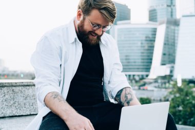 Neşeli sakallı bir adam kendi blog sayfasında yayınlamak için metin bilgileri yazıyor olumlu eleştiriler ve yorumlardan kendini iyi hissediyor, mutlu erkek serbest çalışan dizüstü bilgisayardaki internet sitelerini tarıyor.