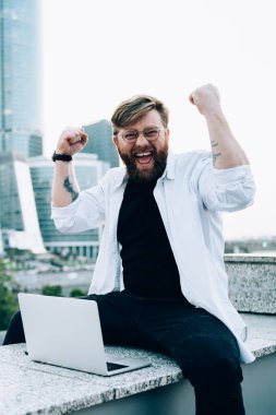 İnternet sitesinde internet bilgisayarında kablosuz internet, mutluluk ve ifade kavramına bağlı bir şekilde otururken hippi bir adamın el kaldırması ve kutlama çığlıkları atması.