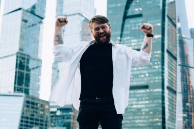 Yeni megalopolis 'i keşfettiği için uluslararası seyahati kutlayan neşeli erkek turistin tam boy portresi. Elleri havada başarılı bir Kafkas gezgini.