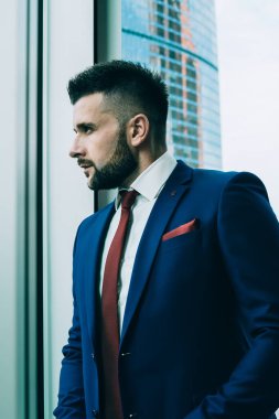 Zarif mavi takım elbiseli ve kırmızı kravatlı yakışıklı işadamı gözlerini kaçırıyor ve çağdaş ofiste zor kararlar veriyor.