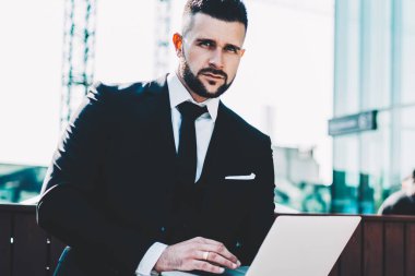 Çevrimiçi araştırmalar için netbook bilgisayarı kullanan yetenekli erkek girişimcilerin portresi yararlı web siteleri hakkında finansal bilgilerle çalışıyor, ciddi bir iş adamı şehir merkezinde kameraya bakıyor.