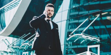 Finansal bölgede yürüyen, resmi lüks takım elbiseli ciddi bir erkek CEO 'su ve şehir merkezindeki buluşma yerini tartışmak için uluslararası cep telefonu sohbeti yapmak için gezici internet bağlantısını kullanıyor.