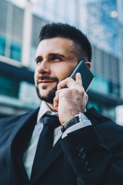 Açık havada dururken cep telefonu cihazıyla iletişim kuran erkek girişimcinin özel bulanık filtresi yakışıklı beyaz tüccar toplantı yerini görüşmek için iş arkadaşına sesleniyor.