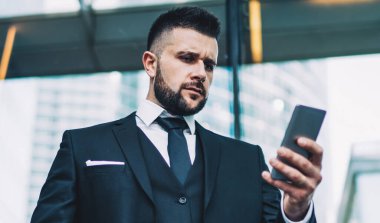 Ciddi bir erkek girişimcinin ofisten iş arkadaşını beklerken cep telefonundan bildirimi kontrol etmesi, iş adamının açık havada uygulamayla gelen e-postayı okuması