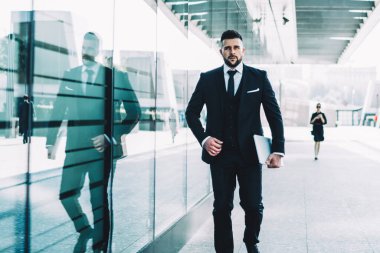 Şık giyinmiş, kendine güveni tam bir erkek avukat elinde online ticaret için modern dizüstü bilgisayarla şehirde dolaşıyor.