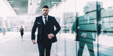 Kendine güveni tam bir erkek şirket sahibi elinde modern netbook ile şehirde yürüyor, ciddi bir beyaz iş adamı resmi pahalı takım elbiseler giymiş finans bölgesindeki şirket konferansına gidiyor.