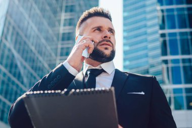 Megalopolis caddesinde muhasebe sırasında cep telefonu ile danışmanlık hizmeti veren düşünceli girişimci, cep telefonu uygulaması üzerinden uluslararası cep telefonu konuşması yapan zeki bir adam.