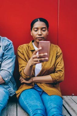 Yakışıklı beyaz erkek kameraya bakarken Afrikalı Amerikalı kız arkadaşı cep telefonuyla konuşuyor gerçek iletişimi görmezden geliyor, çok ırklı çift modern hücrelileri kullanarak birlikte vakit geçiriyor.