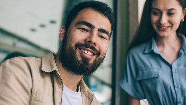 Düşük açılı etnik erkek, gülümseyen ve kameraya bakarken kadın iş arkadaşına sokakta veri toplamada yardım ediyor.