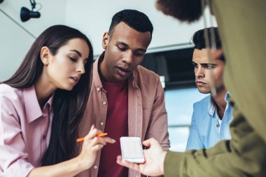 Milenyum hipster çalışanları cep telefonu uygulamasını kontrol ediyor. İnternete bağlı 4G kablosuz internete bağlanıyor. Erkek ve kadın blogcular akıllı telefon uygulaması yüklemek için akıllı telefon kullanıyor.