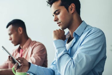 Milenyum İspanyol programcı, modern çalışma alanındaki masa başında çalışırken akıllı telefon uyarısını kontrol ediyor, genç erkek, mobil internet sitesinde pazar haberleri okuyor, 4G 'ye bağlı.