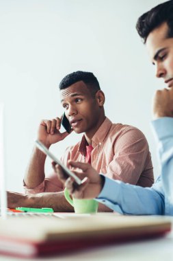 Sıkı çalışma konsepti, iş sorunlarını çözmek için akıllı telefon cihazları kullanan çok ırklı erkek çalışanlar, cep telefonu uygulaması üzerinden e-postaları kontrol eden adam ve operatöre yakın ciddi meslektaşlar.