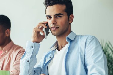 Çevrimiçi iletişim uygulaması üzerinden mobil konuşma yaparken kameraya bakan genç erkek yöneticinin portresi, milenyum pazarlamacısı meslektaşıyla işbirliği hakkında konuşuyor