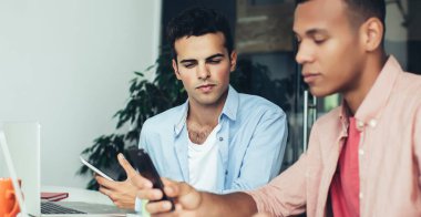 Modern dizüstü bilgisayarlarla masaüstünde oturan çok ırklı ofis çalışanları ve başlangıç için araştırma bilgileri için web sitelerine bakıyorlar, yetenekli erkekler başvuru yoluyla mesajlaşmak için zaman harcıyorlar