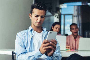 Erkek çalışanın iş günü internet üzerinden para transferi için bankacılık başvurusu yapması, cep telefonu cihazıyla İspanyol yöneticinin kablosuz mesajlaşma sırasında posta kutusunu kontrol etmesi